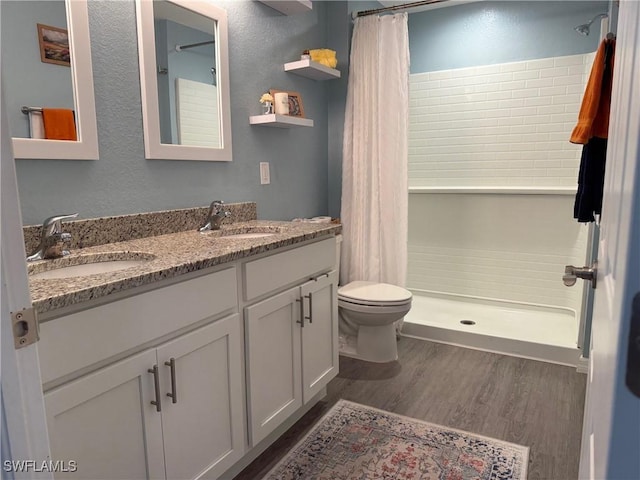 bathroom with double vanity, wood finished floors, a stall shower, and a sink