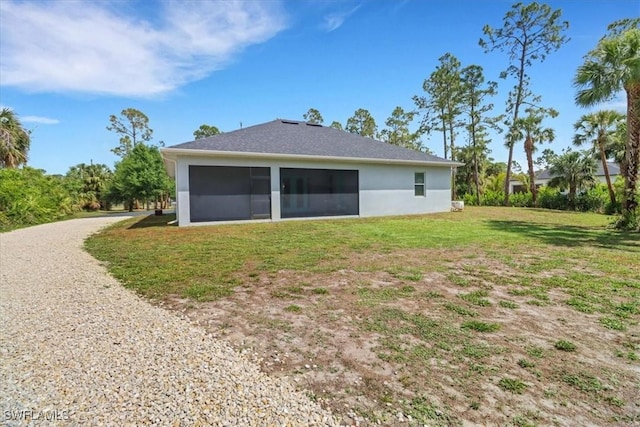 2312 4th Ave SE, Naples, FL 34117 - rear view of property featuring driveway, stucco siding, a sunroom, and a lawn