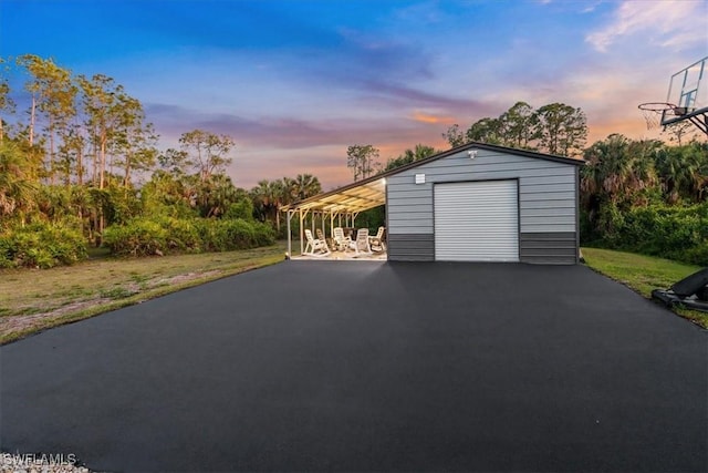 2312 4th Ave SE, Naples, FL 34117 - garage at dusk with a yard, a garage, and aphalt driveway