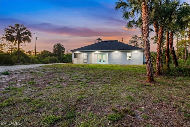 2312 4th Ave SE, Naples, FL 34117 - back of property at dusk with french doors, stucco siding, and a lawn