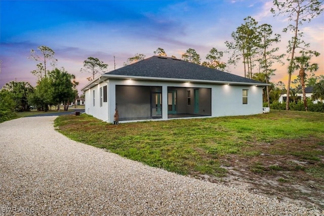 2312 4th Ave SE, Naples, FL 34117 - back of property at dusk with a yard, driveway, stucco siding, and a sunroom