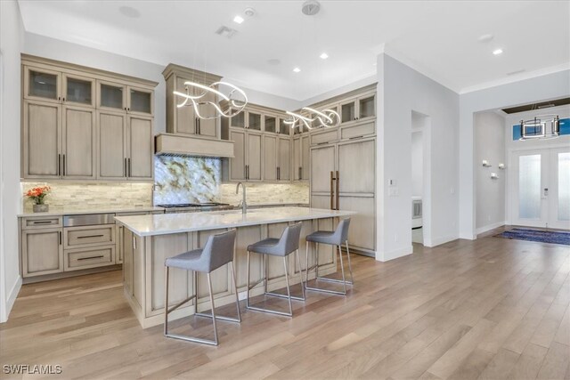 3721 Sapphire Cove Cir, Naples, FL 34114 - kitchen featuring a chandelier, decorative backsplash, a kitchen island with sink, a kitchen bar, and light wood-type flooring