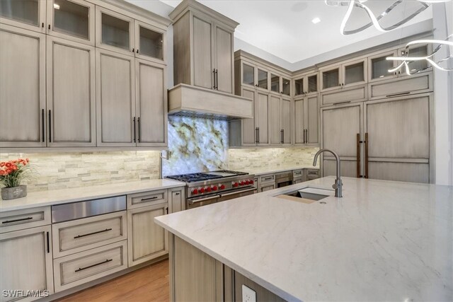 3721 Sapphire Cove Cir, Naples, FL 34114 - kitchen featuring a chandelier, range with two ovens, a sink, light stone countertops, and backsplash