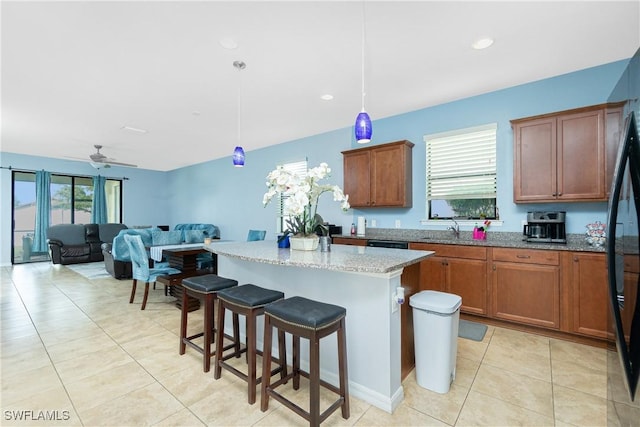 2628 Sherman Oak Dr, North Port, FL 34289 - kitchen with light tile patterned floors, light stone countertops, a sink, a kitchen breakfast bar, and a center island