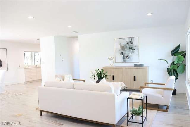 living room with recessed lighting, baseboards, and light wood-type flooring