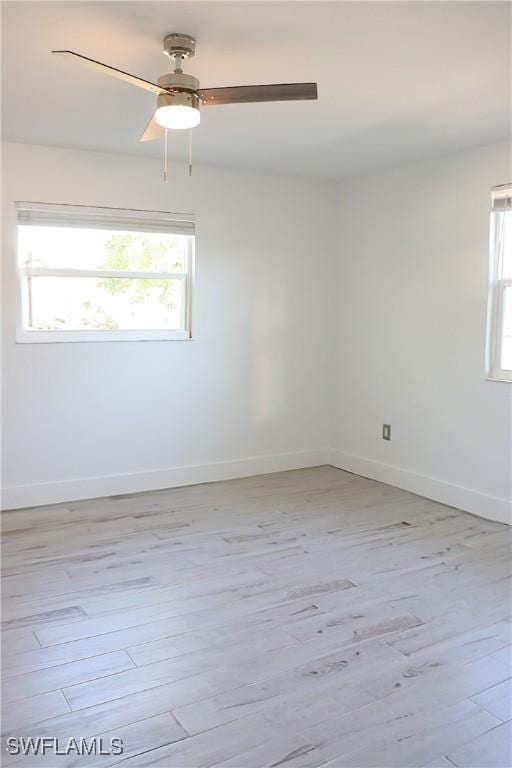 empty room featuring baseboards, ceiling fan, and light wood-style floors