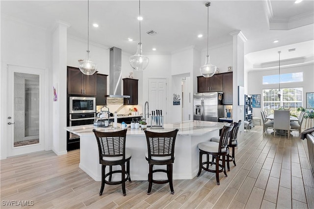 kitchen featuring backsplash, appliances with stainless steel finishes, wall chimney exhaust hood, and wood tiled floor