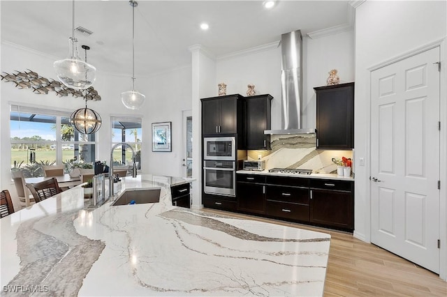 kitchen with ornamental molding, appliances with stainless steel finishes, wall chimney range hood, and a sink