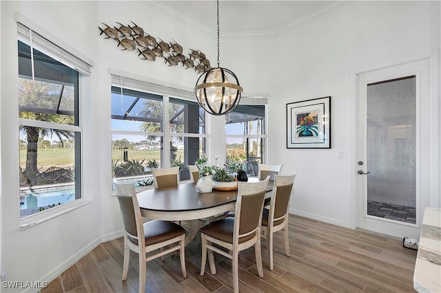 dining space with a notable chandelier, light wood-type flooring, baseboards, and ornamental molding