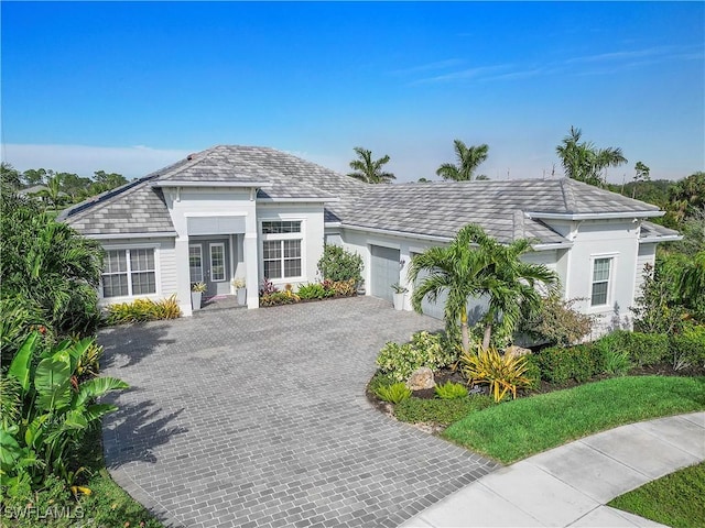 ranch-style home featuring decorative driveway, an attached garage, and stucco siding