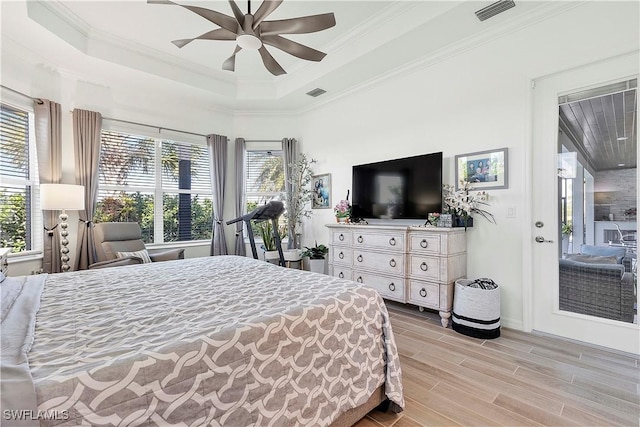 bedroom featuring visible vents, multiple windows, a tray ceiling, and wood finish floors