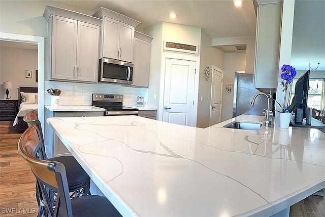 411 SW 19th Ter, Cape Coral, FL 33991 - kitchen featuring tasteful backsplash, light stone counters, wood finished floors, stainless steel appliances, and a sink