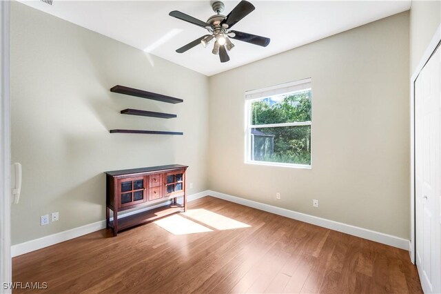 1420 14th Ave NE, Naples, FL 34120 - unfurnished bedroom with wood finished floors, baseboards, a closet, and a ceiling fan