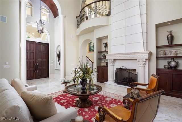 23771 Tuscany Way, Bonita Springs, FL 34134 - living area with decorative columns, built in shelves, a large fireplace, marble finish floor, and arched walkways