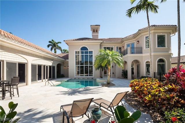 23771 Tuscany Way, Bonita Springs, FL 34134 - back of house featuring a tile roof, stucco siding, a balcony, a patio, and an outdoor pool