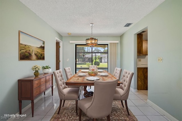 2220 SE 2nd Ter, Cape Coral, FL 33990 - dining area with a textured ceiling, light tile patterned floors, baseboards, and a chandelier