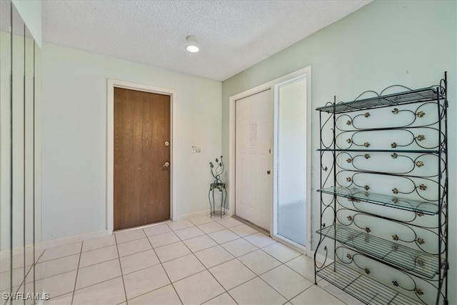 2220 SE 2nd Ter, Cape Coral, FL 33990 - foyer with a textured ceiling, light tile patterned floors, and baseboards