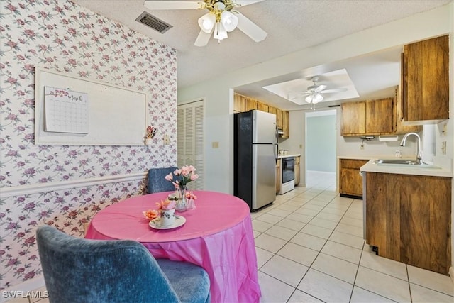 2220 SE 2nd Ter, Cape Coral, FL 33990 - kitchen with freestanding refrigerator, a sink, wallpapered walls, brown cabinets, and a ceiling fan