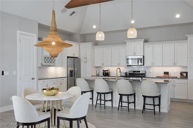 42207 Lake Timber Dr, Punta Gorda, FL 33982 - kitchen featuring a breakfast bar area, a center island with sink, visible vents, beam ceiling, and stainless steel appliances