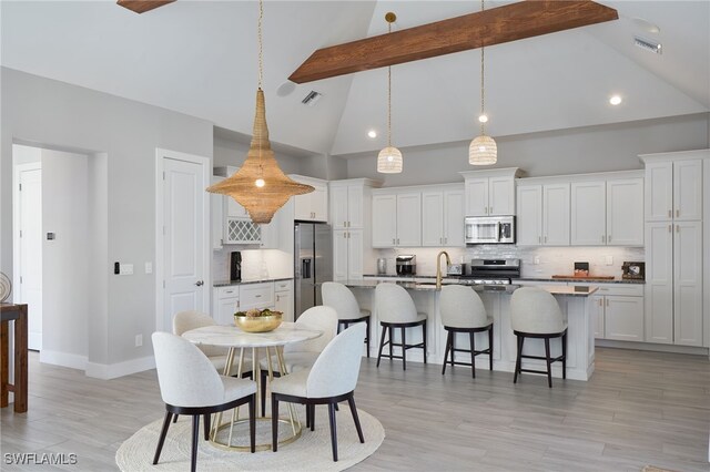 42207 Lake Timber Dr, Punta Gorda, FL 33982 - dining area with light wood finished floors, visible vents, beamed ceiling, and high vaulted ceiling