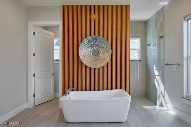 42207 Lake Timber Dr, Punta Gorda, FL 33982 - bathroom featuring a freestanding tub, baseboards, wood finished floors, and a shower stall