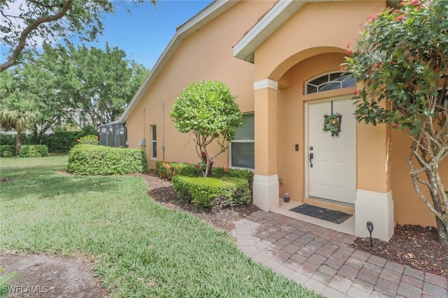 15501 Cortona Way, Naples, FL 34120 - view of exterior entry with stucco siding and a lawn