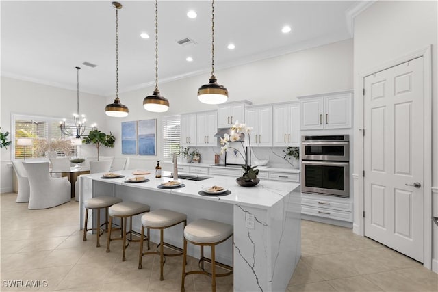 kitchen featuring crown molding, a kitchen bar, visible vents, a sink, and stainless steel double oven