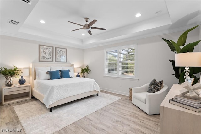 bedroom with a tray ceiling, recessed lighting, visible vents, and light wood-style flooring