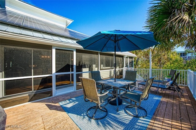 wooden terrace with outdoor dining area and a sunroom