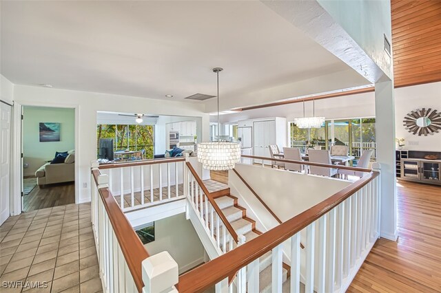 stairway with visible vents, a healthy amount of sunlight, an inviting chandelier, and wood finished floors