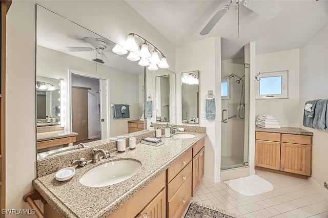 bathroom with double vanity, a sink, tile patterned flooring, a shower stall, and ceiling fan