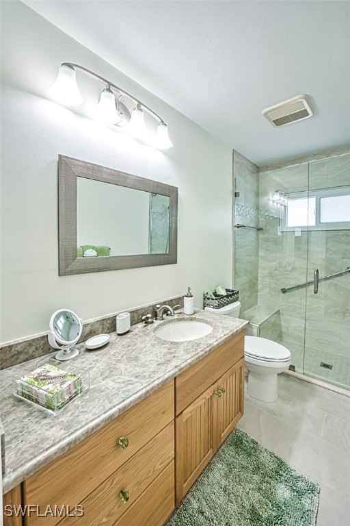 bathroom featuring vanity, a shower stall, toilet, and visible vents