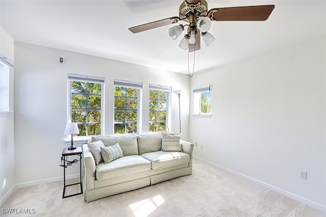 living area featuring light carpet, baseboards, and ceiling fan