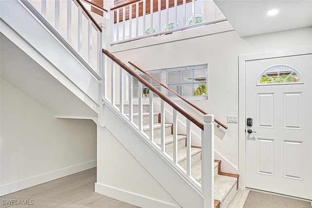 entrance foyer with stairway, baseboards, a high ceiling, and wood finished floors