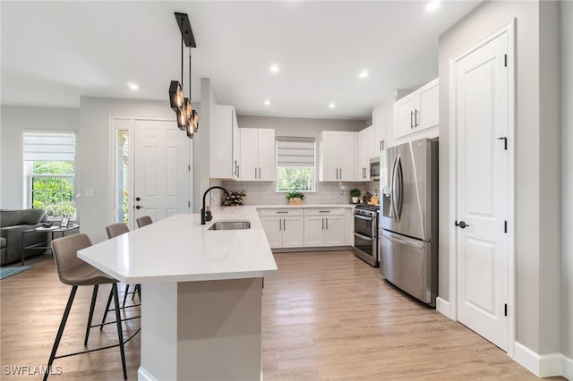 8021 Calle Canovas Ct, Naples, FL 34114 - kitchen with appliances with stainless steel finishes, a sink, a peninsula, a breakfast bar, and decorative backsplash