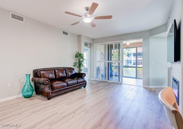 living room featuring wood finished floors, visible vents, a ceiling fan, and baseboards