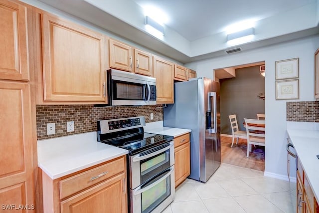 kitchen featuring light countertops, light brown cabinetry, stainless steel appliances, and tasteful backsplash