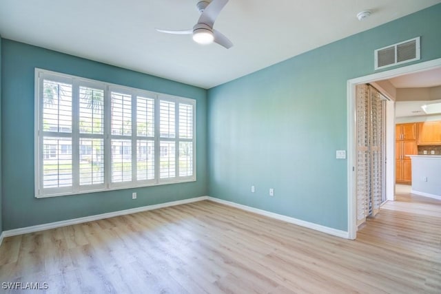 unfurnished room featuring visible vents, ceiling fan, light wood-style flooring, and baseboards