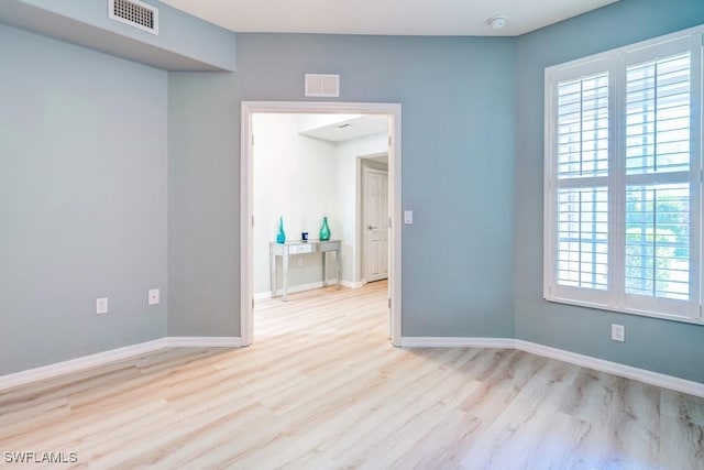unfurnished room featuring visible vents, a wealth of natural light, and wood finished floors