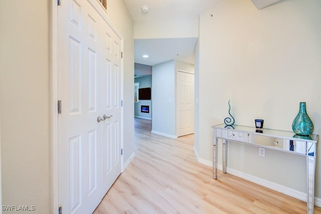 hallway featuring baseboards, recessed lighting, and light wood-style floors
