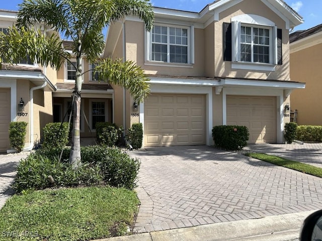 view of front facade featuring stucco siding, decorative driveway, and a garage