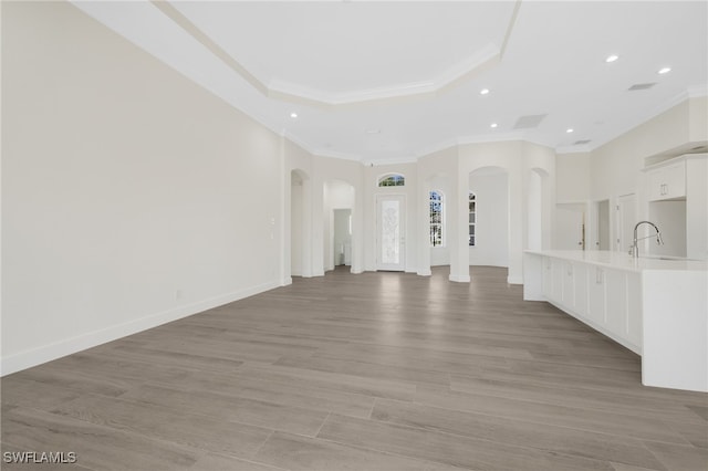 16404 Coco Hammock Way, Fort Myers, FL 33908 - unfurnished living room featuring ornamental molding, arched walkways, recessed lighting, light wood-style floors, and a raised ceiling