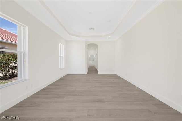 16404 Coco Hammock Way, Fort Myers, FL 33908 - unfurnished room with arched walkways, a raised ceiling, plenty of natural light, ornamental molding, and light wood-style floors