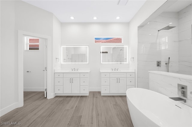 16404 Coco Hammock Way, Fort Myers, FL 33908 - bathroom featuring wood finished floors, a soaking tub, a marble finish shower, two vanities, and recessed lighting