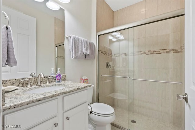 full bathroom featuring vanity, a shower stall, and toilet