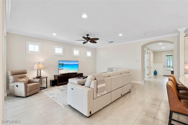 living room featuring visible vents, arched walkways, ornamental molding, and a ceiling fan