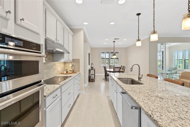 kitchen with a wealth of natural light, under cabinet range hood, a sink, tasteful backsplash, and appliances with stainless steel finishes