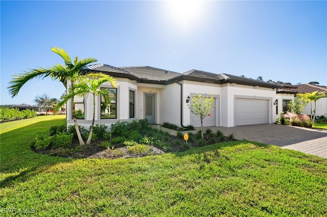 view of front of home with a garage, decorative driveway, a front lawn, and stucco siding