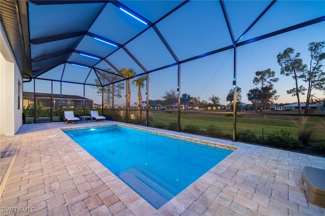 pool at dusk with a yard, a lanai, and a patio area