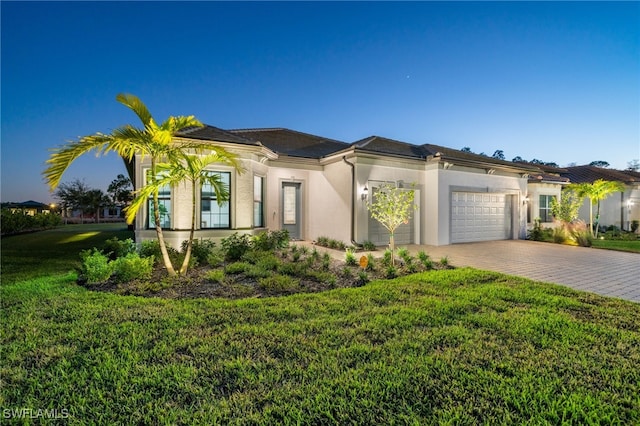 view of front of home with stucco siding, a front yard, decorative driveway, and a garage